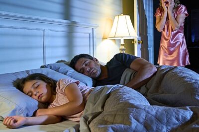 An eight-year-old girl sleeps alone, but every morning she complains that her bed feels “too small.” When her mother checks the security camera at 2 a.m., she breaks down in silent tears….
